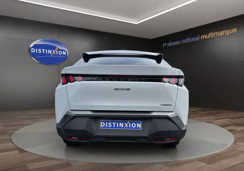 Vue arrière d’un Peugeot 3008 blanc hybride 2025 avec feux arrière LED et logo distinctif sur fond showroom.