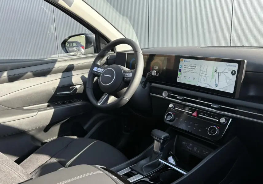 Intérieur du Hyundai Tucson 2025 vu côté conducteur, tableau de bord moderne avec écran tactile panoramique.