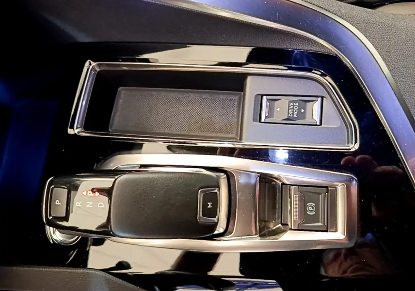 Gros plan sur la console centrale noire brillante du Peugeot 5008 2021 avec levier de boîte auto et boutons Drive Mode et frein électrique.
