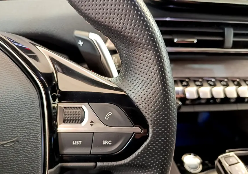 Gros plan sur la partie gauche du volant perforé noir du Peugeot 5008 GT Pack 2021, avec commandes intégrées.