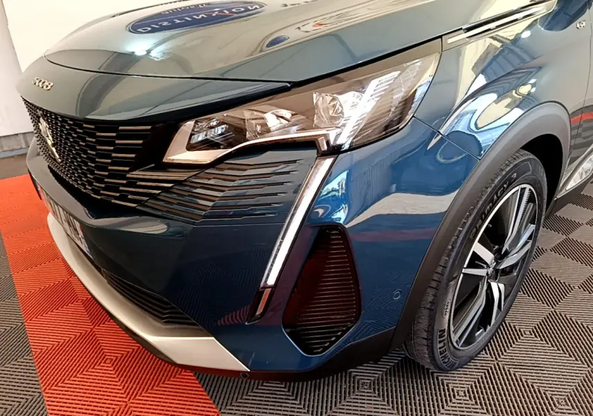 Gros plan sur l'avant droit bleu du Peugeot 5008 GT Pack 2021 avec phares LED et calandre noire distinctive.