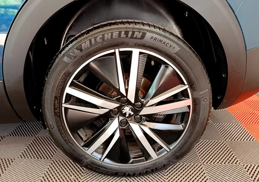 Gros plan sur la roue avant droite du Peugeot 5008 bleu, mettant en valeur la jante alliage bicolore et le pneu Michelin.