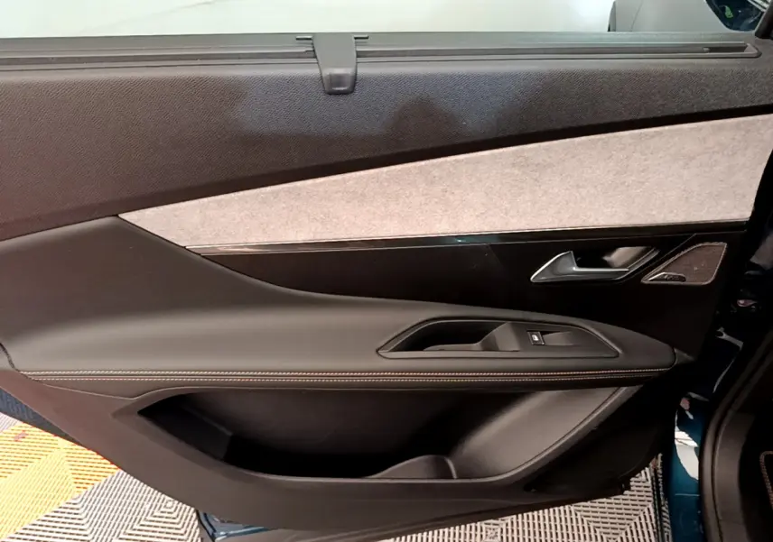 Vue intérieure de la porte arrière droite du Peugeot 5008 bleu, avec garniture tissu et cuir noir.