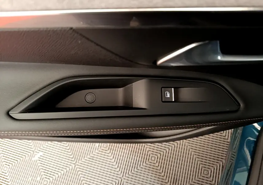 Poignée intérieure côté gauche de la porte d'un Peugeot 5008 bleu, avec bouton de verrouillage et surpiqûres marron.