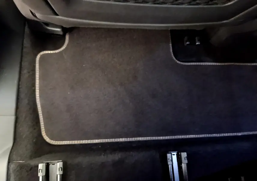 Gros plan sur le plancher arrière noir avec tapis et rails d'ancrage des sièges du Peugeot 5008 bleu.
