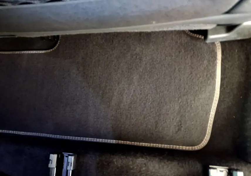 Gros plan sur le tapis de sol noir avec surpiqûres beiges dans l'habitacle du Peugeot 5008 bleu 2021.