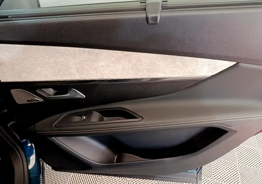 Gros plan sur la porte côté gauche du Peugeot 5008 bleu, avec garniture noire et insert tissu clair.