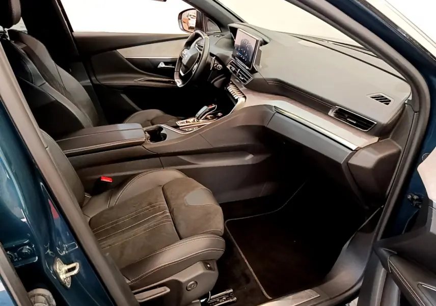 Vue intérieure côté conducteur du Peugeot 5008 bleu 2021, avec tableau de bord moderne et sièges en cuir noir.