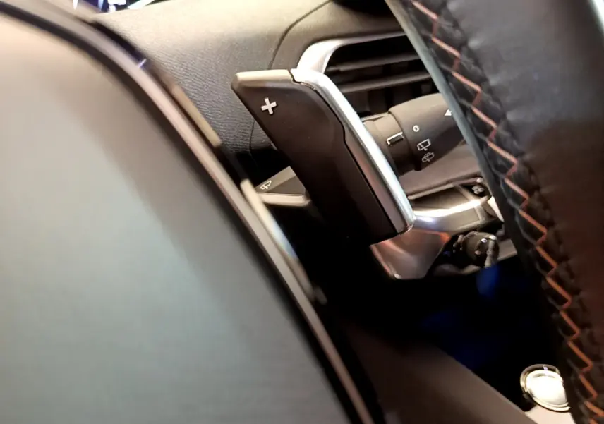 Gros plan sur la palette de changement de vitesse droite du volant cuir noir du Peugeot 5008 bleu, version GT Pack.