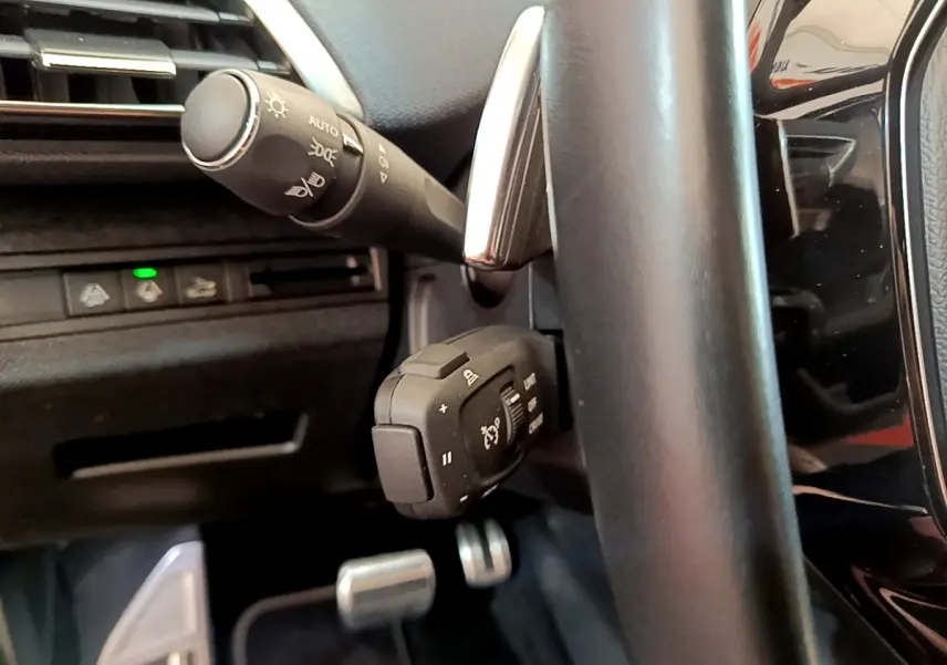 Gros plan sur la commande multifonction et levier de clignotant côté gauche du volant cuir noir du Peugeot 5008 GT Pack bleu 2021.