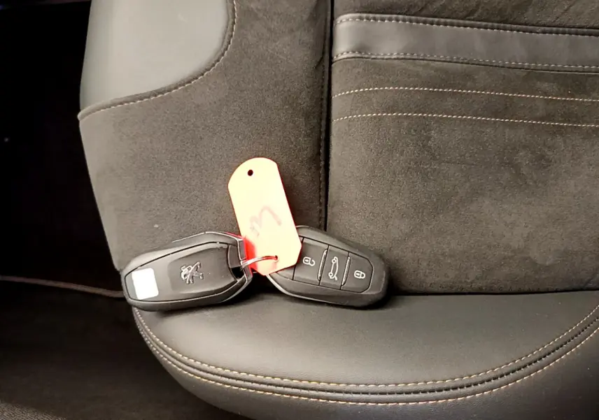 Gros plan sur la clé Peugeot posée sur un siège en cuir et alcantara noir avec surpiqûres marron du 5008 GT Pack 2021