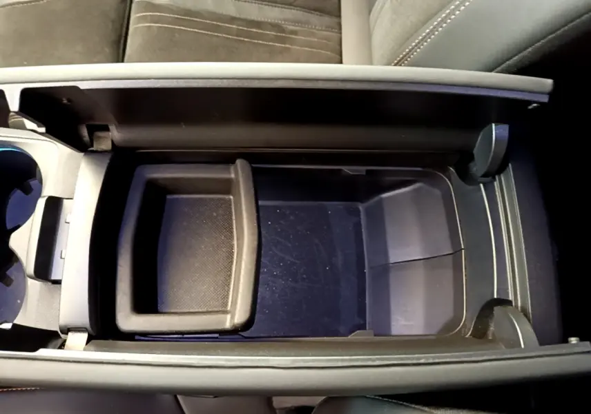 Vue plongeante sur le rangement central noir ouvert du Peugeot 5008 GT Pack 2021, sièges en tissu gris visible.