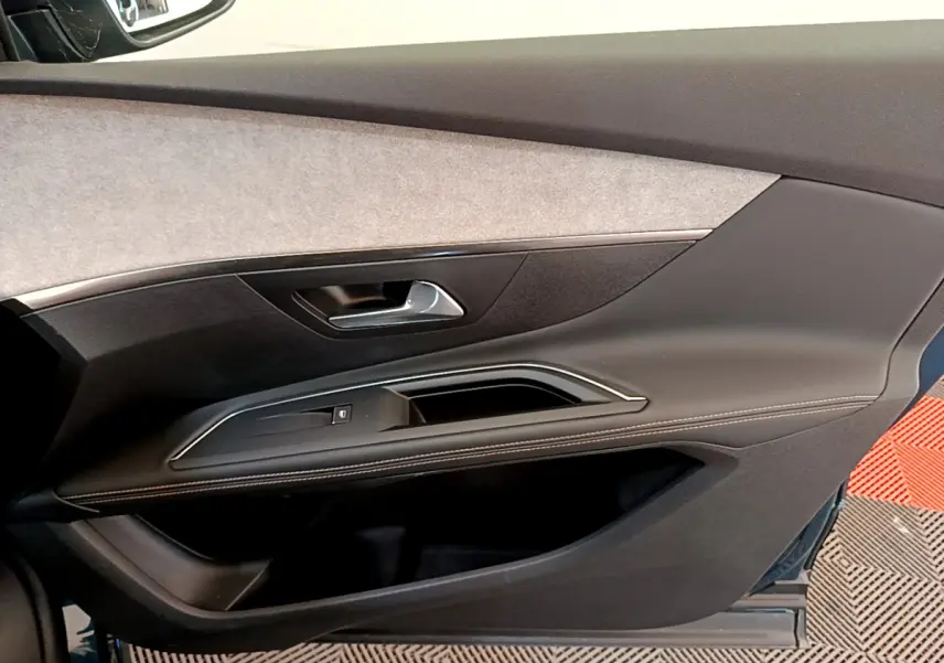 Gros plan sur la garniture de la porte côté droit du Peugeot 5008 bleu, avec insert tissu clair et surpiqûres blanches.