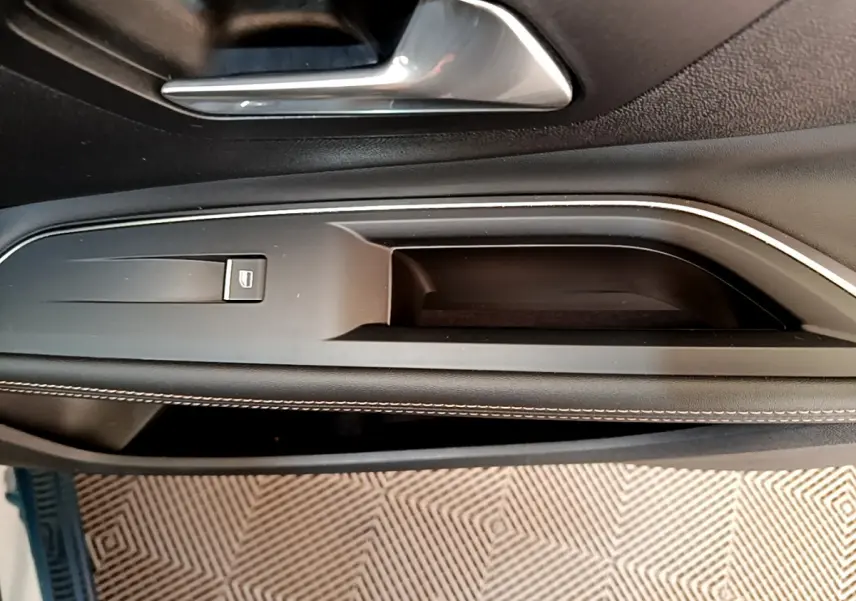 Poignée intérieure côté gauche de porte noire avec surpiqûres blanches sur Peugeot 5008 bleu 2021.