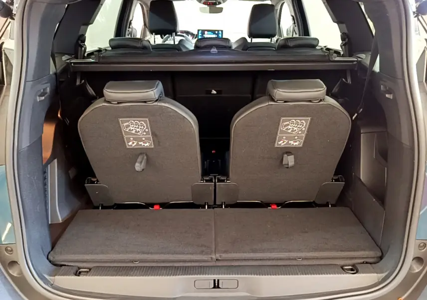 Vue arrière du coffre ouvert d'un Peugeot 5008 bleu 2021, montrant la 3ème rangée de sièges individuels rabattus.