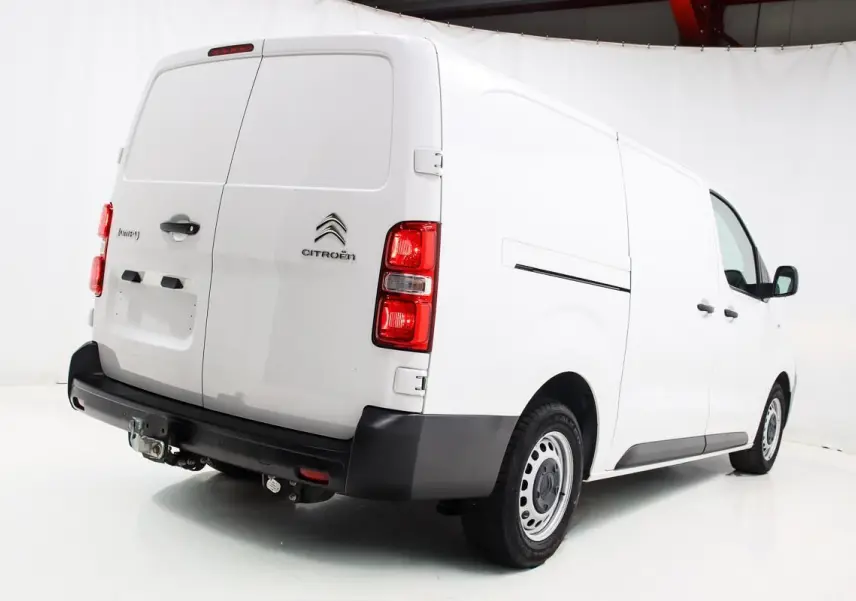 Vue 3/4 arrière droite d'un fourgon Citroën Jumpy blanc avec attelage et portes arrière battantes.