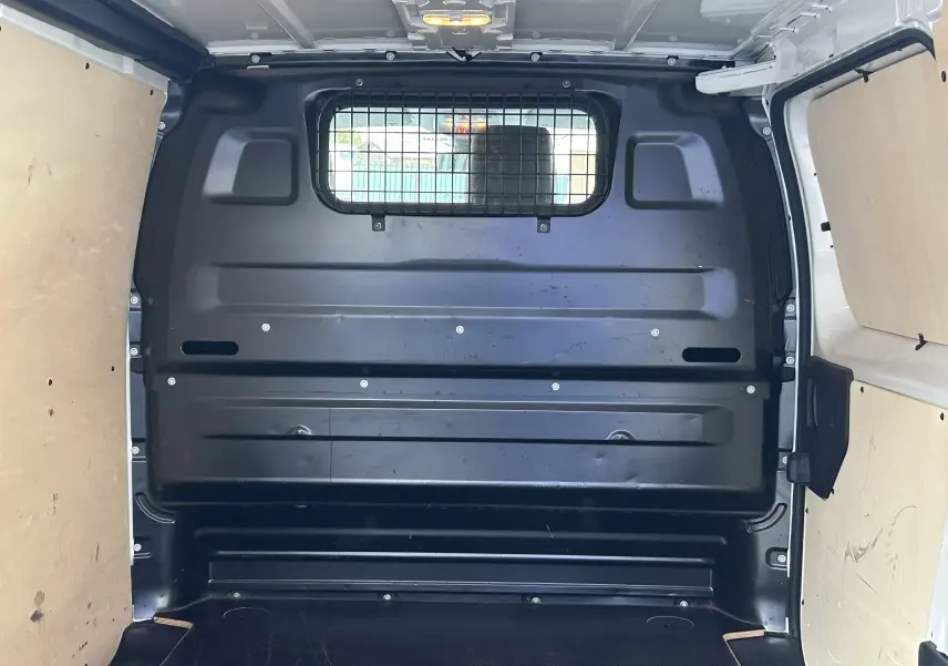 Vue intérieure arrière du fourgon blanc Citroën Jumpy XL 2019, montrant la cloison métallique avec grille de séparation.