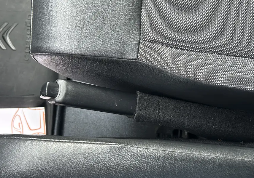 Gros plan intérieur sur le frein à main entre les sièges tissu gris et noir du Citroën Jumpy Fourgon XL blanc.