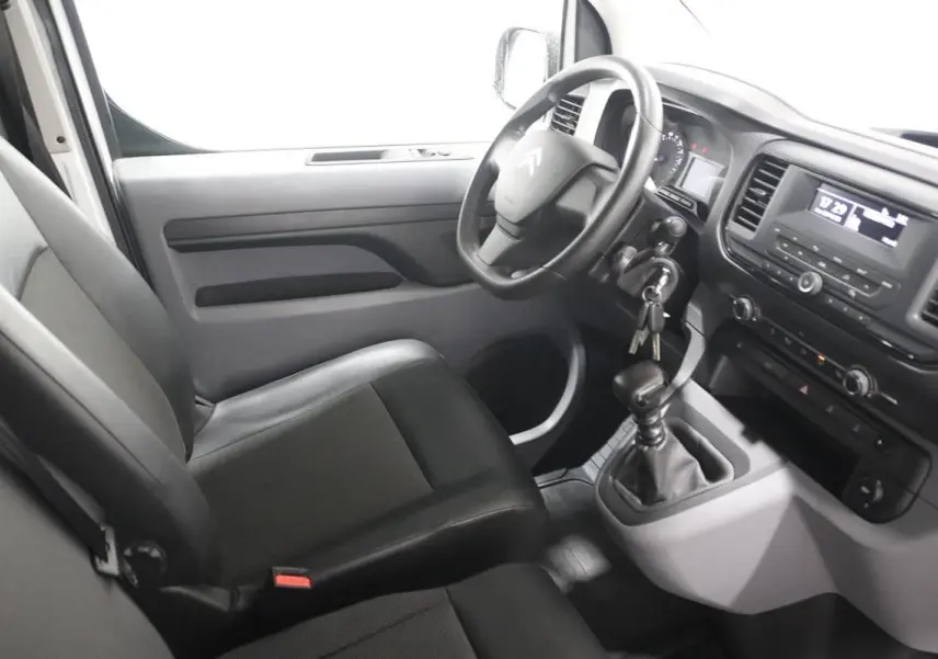 Vue intérieure côté conducteur du Citroën Jumpy blanc, montrant le volant, tableau de bord et levier de vitesse manuel.