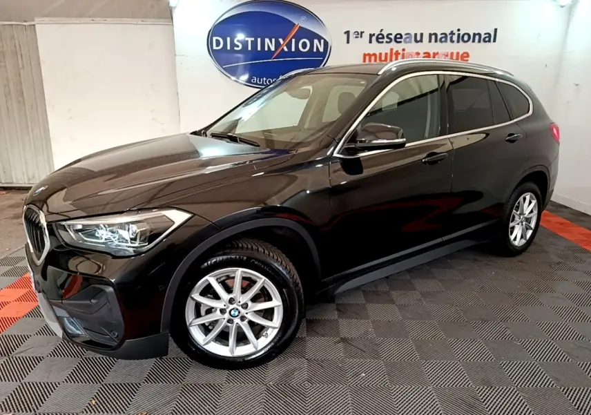 BMW X1 noir vue 3/4 avant droit, mettant en valeur ses phares LED et jantes alliage argentées.