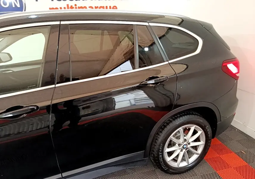 Vue latérale côté droit d'un BMW X1 noir 2020 avec jante alliage et feux arrière allumés.