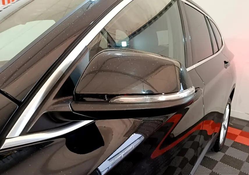 Gros plan sur le rétroviseur côté gauche noir brillant du BMW X1 sDrive16d Business Design 2020.