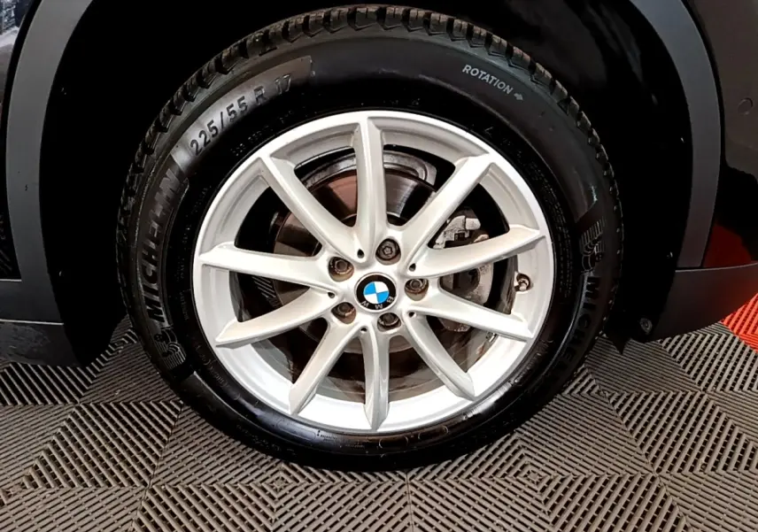 Gros plan sur la roue avant droite d’un BMW X1 noir avec jante alliage argent et pneu Michelin.