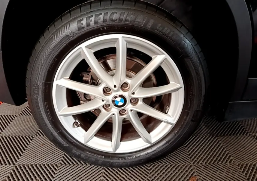 Gros plan sur la roue avant droite noire d'un BMW X1 2020 avec jante argentée à 7 branches fines