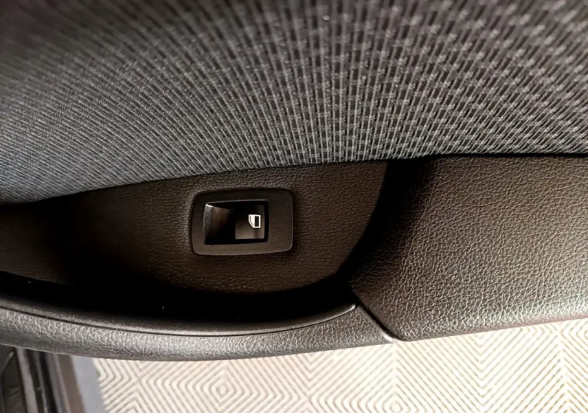 Gros plan sur le bouton de commande de lève-vitre noir, côté intérieur d'une BMW X1 sDrive16d Business Design 2020.