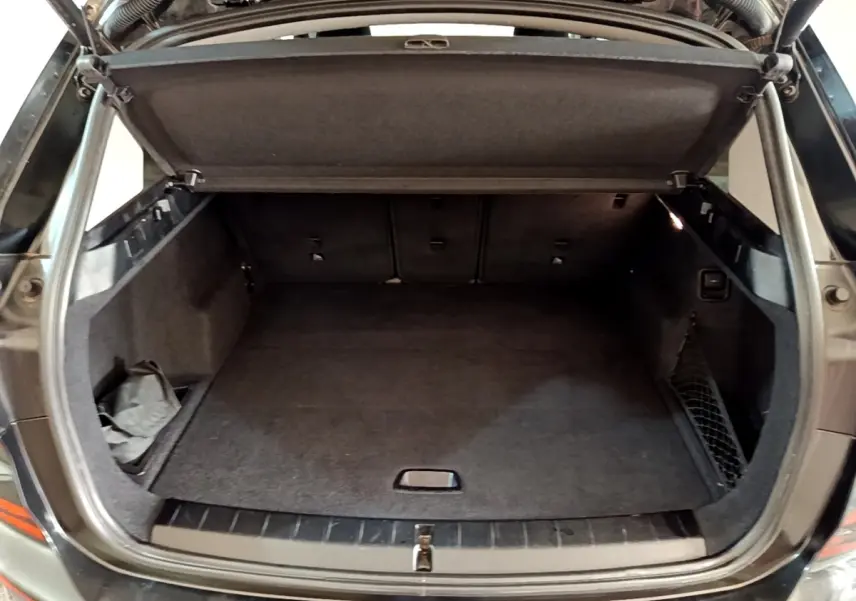 Coffre ouvert vu de l'arrière du BMW X1 noir, montrant un espace de chargement propre et bien agencé.