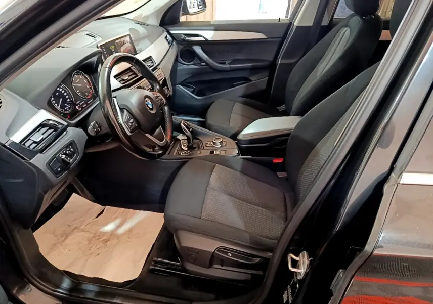 Intérieur avant droit d'une BMW X1 noir 2020, volant cuir multifonctions et écran tactile 8,8 pouces visible.