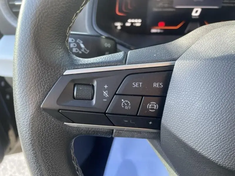 Gros plan sur les commandes au volant côté gauche du SEAT Arona noir 2023, avec boutons de régulateur de vitesse et volume.