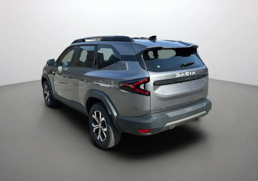 Vue 3/4 arrière droite du SUV Dacia Bigster gris schiste avec barres de toit et jantes alu 17 pouces.