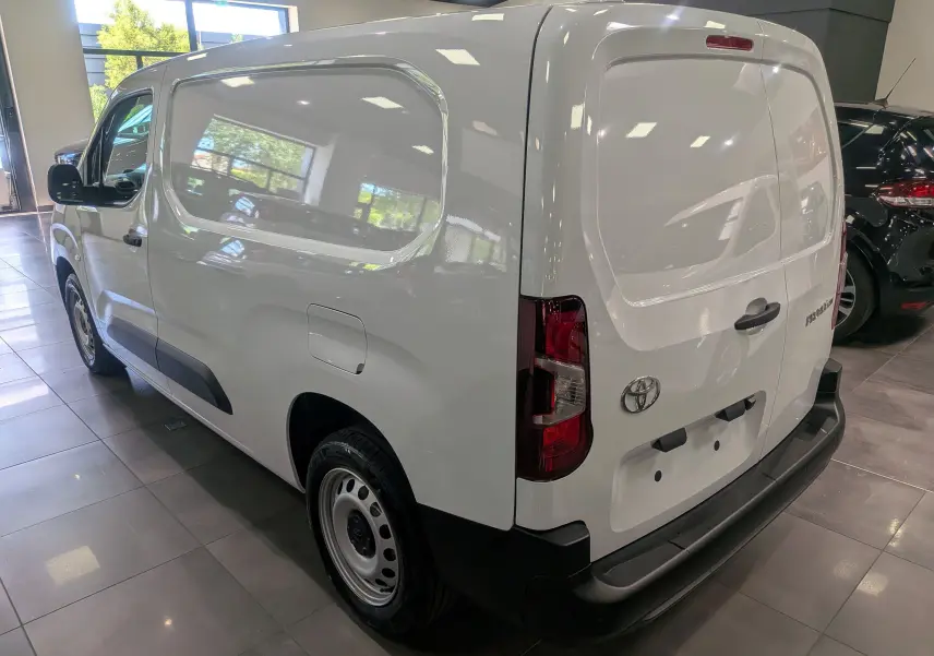 Vue 3/4 arrière droite du Toyota Proace City Long blanc Glacier, fourgon utilitaire avec hayon arrière et protections noires.