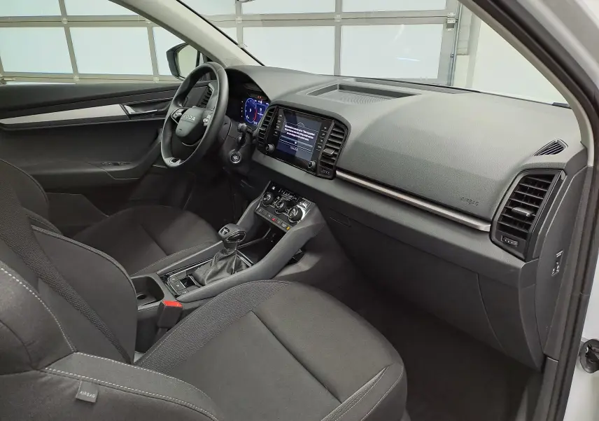 Vue intérieure côté conducteur du Skoda Karoq 2025 blanc lune, avec tableau de bord digital et console centrale moderne.