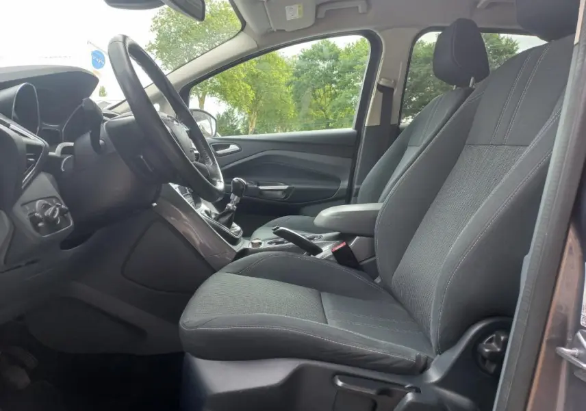 Intérieur avant droit du Ford C-MAX gris 2015, montrant sièges tissu noirs et tableau de bord avec boîte manuelle.