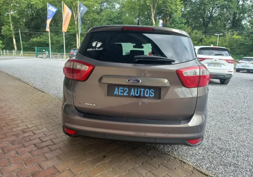 Vue arrière d'une Ford C-MAX gris 2015 avec autocollant "Bébé à bord" sur la vitre arrière.