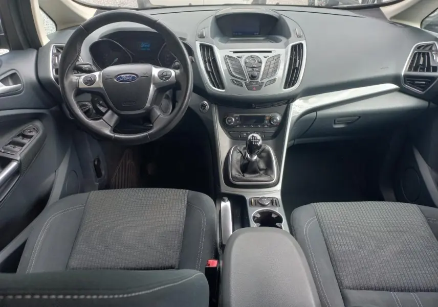 Vue intérieure avant du Ford C-MAX gris 2015, avec volant, tableau de bord et levier de vitesse manuel visibles.