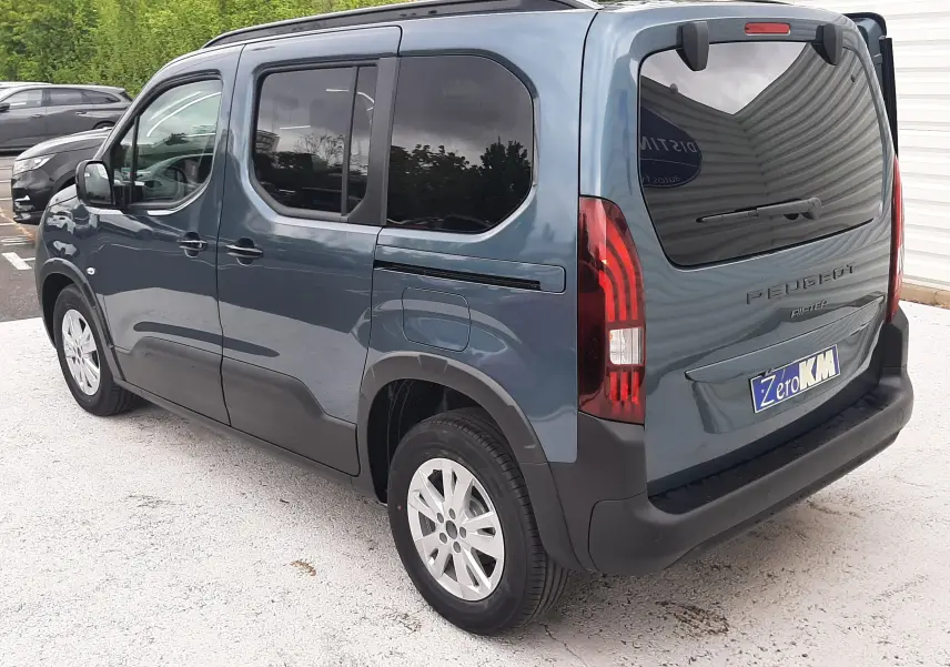 Vue 3/4 arrière droite du Peugeot Rifter bleu Kiama avec vitres arrière surteintées et jantes alu 16 pouces.