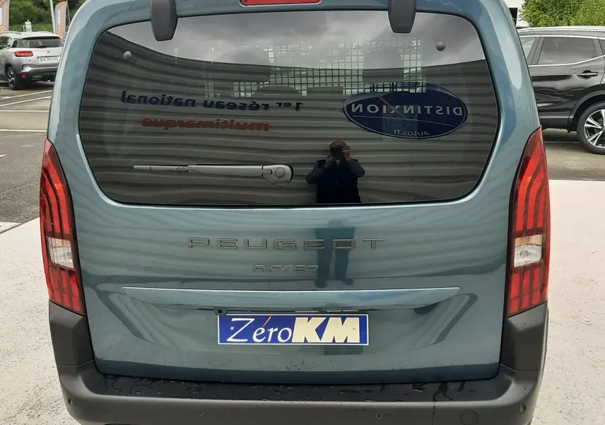 Vue arrière d'un Peugeot Rifter bleu Kiama 2026 avec lunette arrière ouvrante et feux verticaux rouges.
