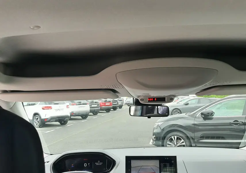 Vue intérieure avant du Peugeot Rifter 2026, montrant le tableau de bord avec écran de caméra de recul et volant.