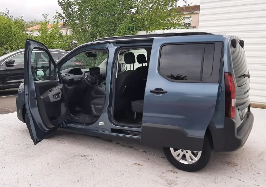 Vue latérale droite d’un Peugeot Rifter bleu Kiama 2026 avec portes avant et latérale gauche ouvertes, montrant l’intérieur.