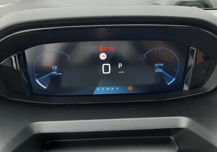 Vue rapprochée du tableau de bord numérique du Peugeot Rifter gris acier, affichant 0 km/h et 75 km d'autonomie restante.