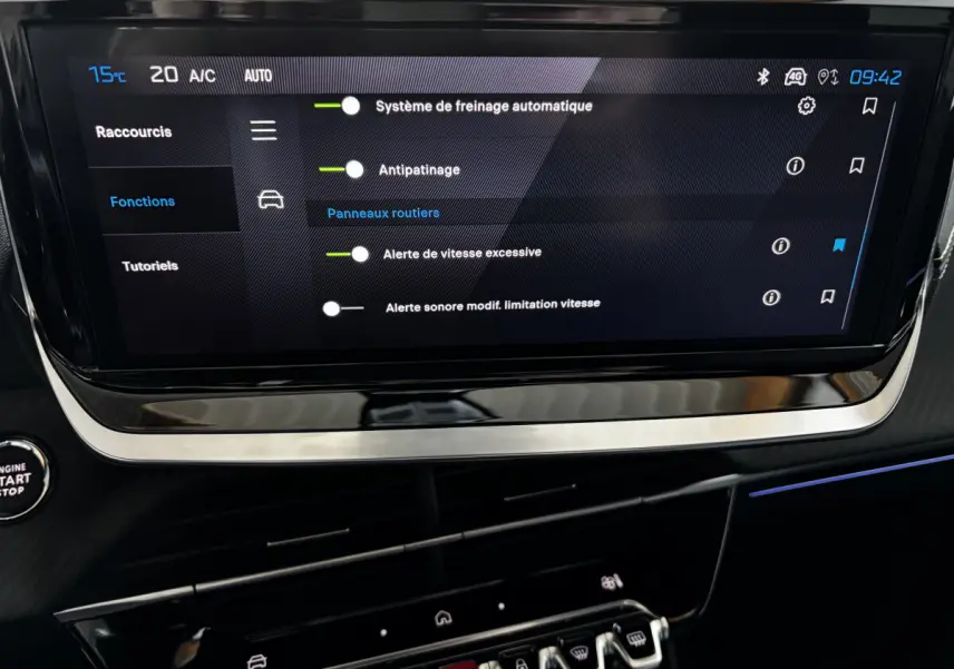 Écran tactile central affichant les réglages d'aide à la conduite dans l'habitacle sombre d'une Peugeot 208 Hybrid 136 eDCS6 GT.