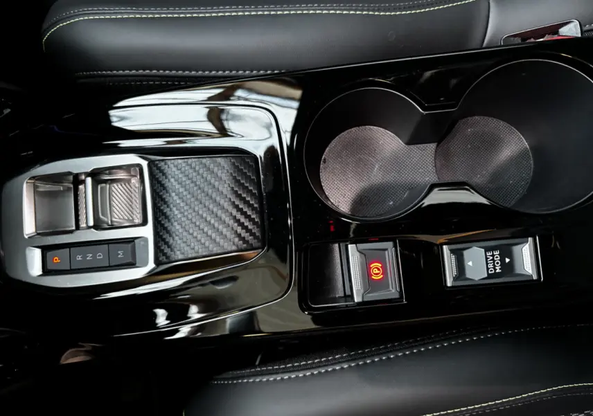 Gros plan sur la console centrale noire brillante de la Peugeot 208 Hybrid 136 eDCS6 GT avec levier de vitesses et boutons électroniques.