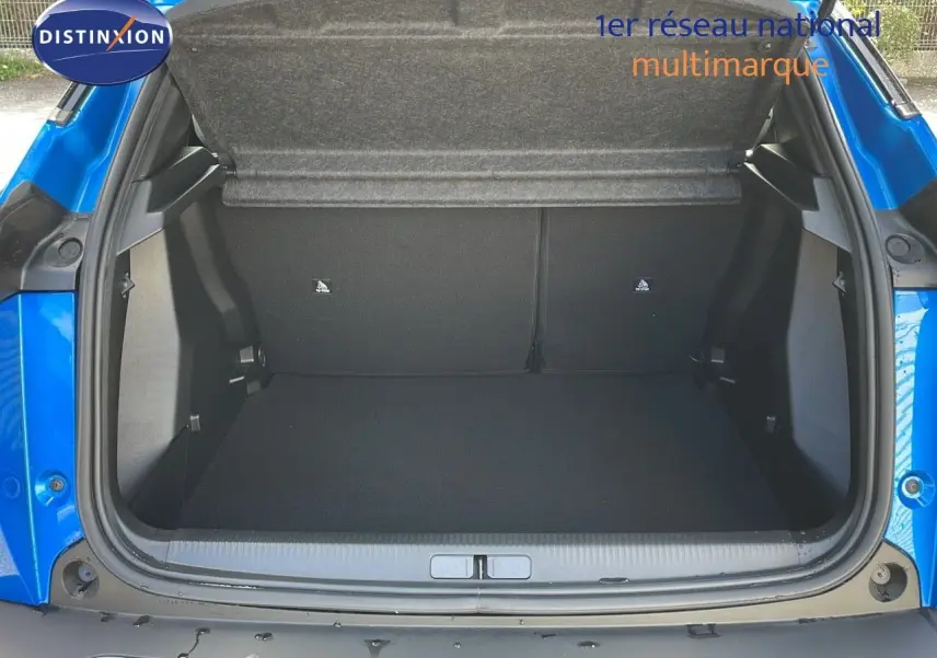 Coffre ouvert d'une Peugeot 2008 2024 bleu Vertigo Metal, vue arrière montrant l'espace de chargement vide.