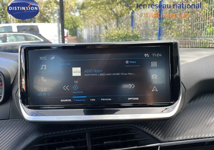 Écran tactile central du tableau de bord du Peugeot 2008 2024, affichant la radio DAB avec interface moderne et finition carbone.