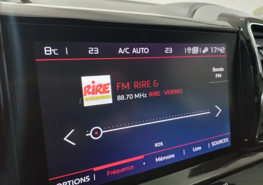 Gros plan sur l'écran tactile central du Citroën C5 Aircross blanc, affichant la radio FM Rire & Chansons.