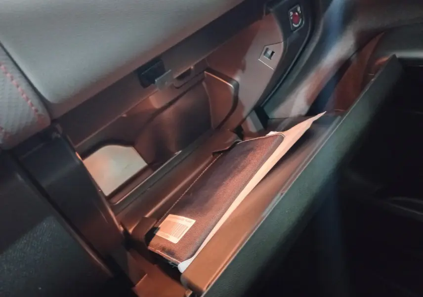 Gros plan sur la boîte à gants ouverte du Citroën C5 Aircross blanc, montrant un manuel dans un étui noir.