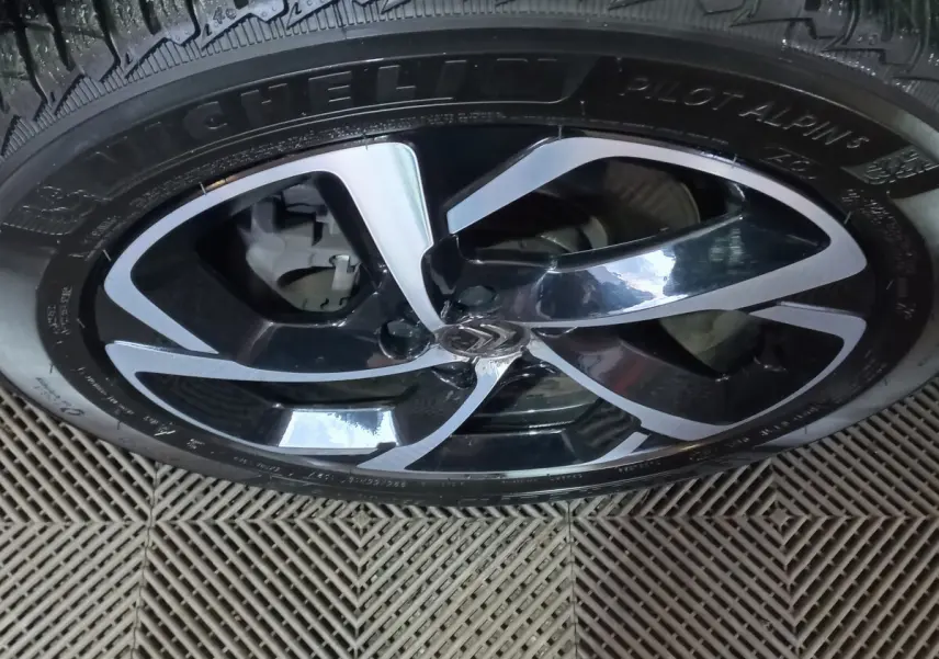 Gros plan sur la jante noire et argentée avec logo Citroën au centre, montée sur un pneu Michelin Pilot Alpin.